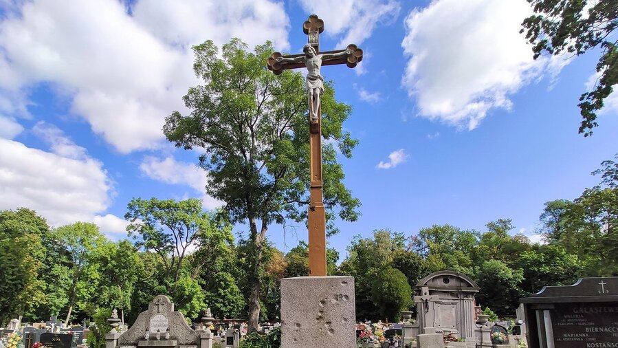 Drewniany Krzyż Katyński posadowiony jest na kamiennym postumencie ze śladami po kulach karabinowych. Po obu stronach podstawy krzyża znajdują się tablice z nazwiskami zamordowanych przez NKWD mieszkańców Ziemi Kościańskiej.