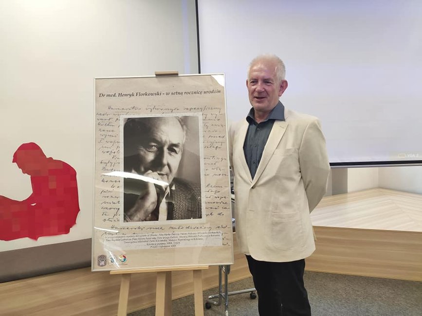 Prof. Andrzej Florkowski przy plakacie reklamującym wystawę poświęconą jego ojcu. 