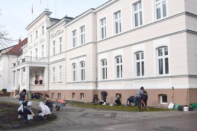 Uczniowie sadzą rośliny przed urzędem